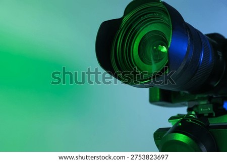 Gimbal stabilizer with camera on light background with green light, closeup. Space for text
