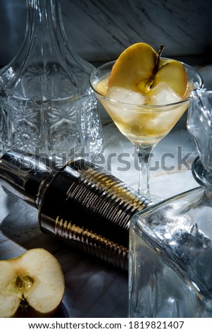 Gin appletini cocktail in martini glass with ice and sliced apple garnish