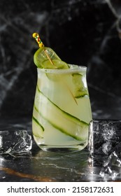 Gin gimlet cocktail garnished with cucumber. Green alcohol cocktail. With a cucumber on a black background