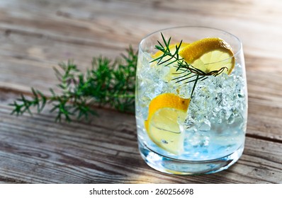 Gin with lemon and juniper branch on a old wooden table