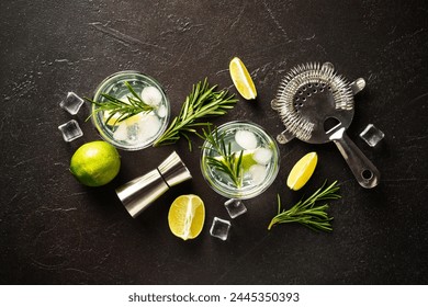 Gin tonic. Alcohol cocktail with gin, tonic, ice cubes, lime and rosemary on black background. Top view with copy space.