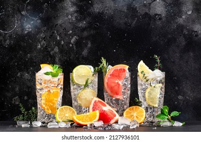 Gin Tonic And Citrus Cocktails Set. Alcoholic Drinks With Lime, Lemon, Grapefruit, Orange, Soda And Herbs In Highball Glasses, Black Bar Counter Background. Summer Cocktail Party