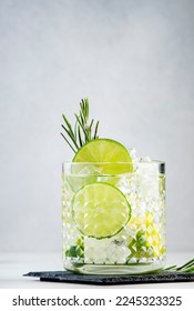 Gin tonic classic alcoholic cocktail drink with dry gin, bitter tonic, lime and ice, bar tools. Gray table background with copy space
