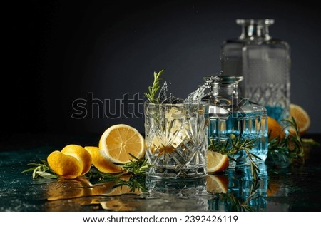 Gin tonic cocktail with lemon and rosemary. Slice of lemon fall in glass with a cocktail.