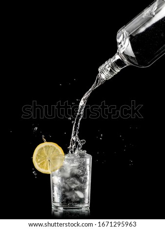 Gin tonic cocktail pouring isolated on black background