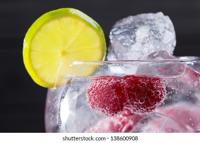 Gin Tonic Cocktail With Raspberry Lima Slice And Ice Macro Closeup On Black