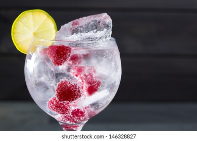 Gin Tonic Cocktail With Raspberry Lima Slice And Ice Macro Closeup On Black