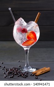 Gin Tonic Cocktail With Strawberries Raspberry Cinnamon And Juniper Berries On Black