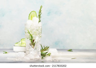 Gin tonic with cucumber, alcoholic cocktail drink with dry gin, rosemary, tonic, fresh cucumber and ice cubes. Gray background, bar tools, copy space