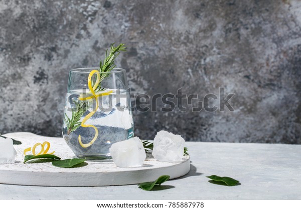 Gin and Tonic drink served with\
ice, lemon zest and fresh rosemary. Drink Concept. Copy\
space
