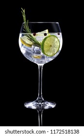 gin tonic garnished with citrus fruit and rosemary isolated on black background