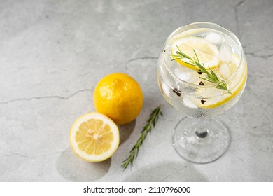Gin Tonic garnished with lemon and rosemary.