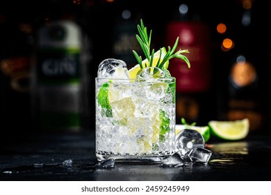 Gin tonic and rosemary cocktail drink with lime juice, sugar syrup, soda and ice. Black bar counter background