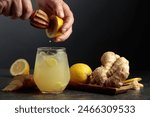 Ginger Ale with ice and lemon. Juice is squeezed out of a lemon with an old wooden juicer.