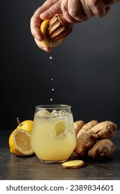Ginger Ale with ice and lemon. Juice is squeezed out of a lemon with an old wooden juicer.