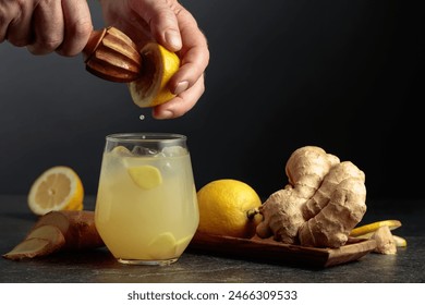 Ginger Ale with ice and lemon. Juice is squeezed out of a lemon with an old wooden juicer. - Powered by Shutterstock