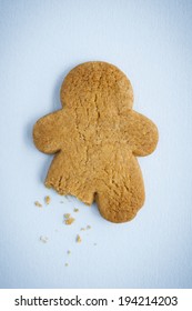 Ginger Bread Man, Isolated On Pale Blue Background, With Right Leg Missing And Crumbs.