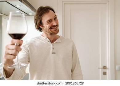 Ginger Bristle Man Smiling And Winking While Drinking Wine In Kitchen At Home