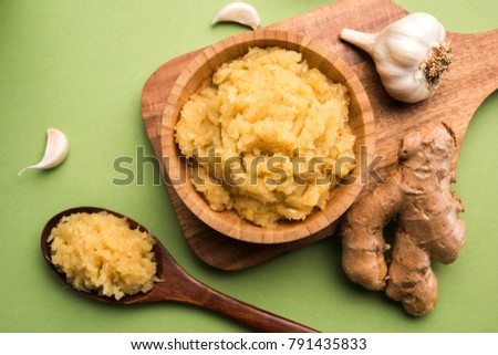 Ginger Garlic paste / Fresh mashed Adrak and Lahsun in wooden bowl and whole. Over moody colourful background. selective focus