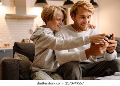 Ginger man using mobile phone while making fun with his son at home