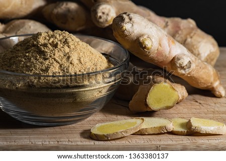 Ginger powder in glass bowl on wooden cutting board with ginger roots and slices. Healthy eating concept. [[stock_photo]] © 