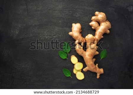 Ginger root with slices and mint leaf on black cement dark background , top view , flat lay.