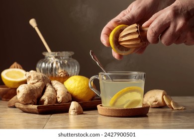 Ginger tea with lemon and honey on a brown ceramic table. Juice is squeezed out of a lemon with an old wooden juicer. - Powered by Shutterstock