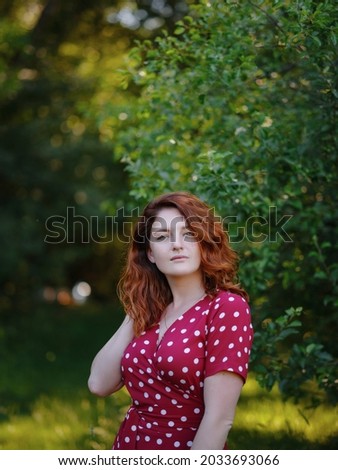Ginger Woman wearing orange dress in green forest enjoys the silence and beauty of nature. idea and concept of wellness, celebration of lifes little moments