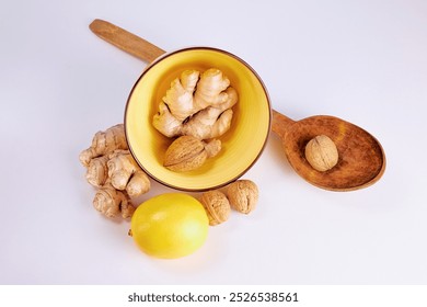 ginger in a yellow deep plate, nut in a large wooden spoon and lemon on a light background, top view - Powered by Shutterstock