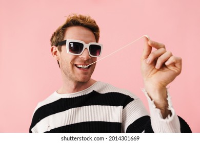 Ginger Young Man Wearing Sunglasses Stretching Bubblegum Isolated Over Pink Wall