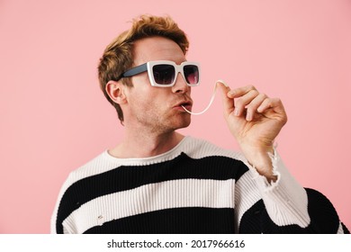 Ginger Young Man Wearing Sunglasses Stretching Bubblegum Isolated Over Pink Wall