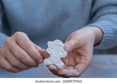 Gingerbread character Creator is using white air dry clay for making decor to Christmas tree holiday. Creating hobby recreation activity that involves fingers. DIY crafting