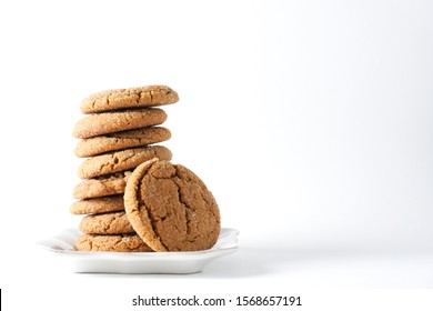 A Gingerbread Cookie Leans On A Stack On Cookies On A White Plate Isolated On A White Background; Copy Space On Right