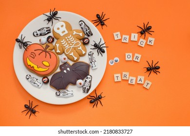 Gingerbread Halloween cookies, black ants decorations and wooden sign trick or treat on an orange background. Halloween concept