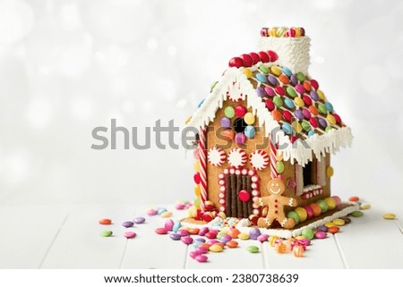 Gingerbread house decorated with colorful candies against a white background