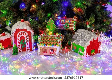 A gingerbread house decorated with colorful garlands and a Christmas tree.
