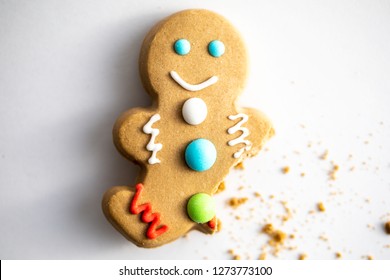 Gingerbread Man With Buttons Shot On A White Background With A Bite Taken Out Of His Broken Leg