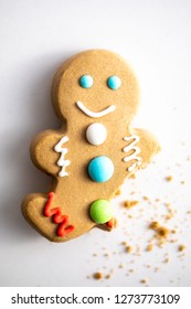 Gingerbread Man With Buttons Shot On A White Background With A Bite Taken Out Of His Broken Leg