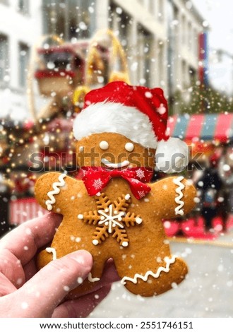 Gingerbread man in hand against the backdrop of a Christmas market. Close-up. Christmas background.