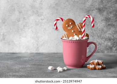 Gingerbread man in a mug with marshmallows and a candy cane, gray background. Christmas symbol. Selective focus. - Powered by Shutterstock