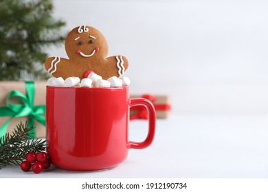 Gingerbread man in red cup with marshmallows on white table, space for text - Powered by Shutterstock