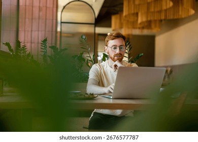 Ginger-haired man working on computer at cafe during lunch