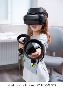 Girl 7 Y.o. Experiencing VR Headset Game At Home. Virtual Technology Simulator. Emotional Kid Exploring Artificial Computer World Or Playing Video Game