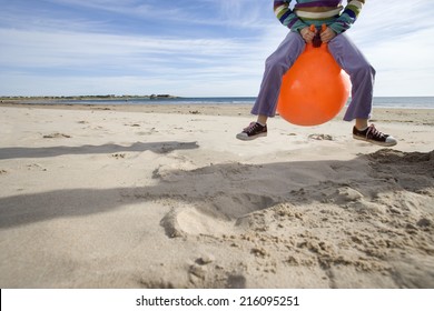 Girl (8-10) Playing On Inflatable Hopper On Beach, Low Section