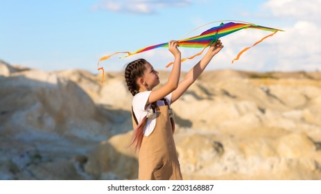 A Girl Of 8-9 Years Old Launches A Kite Into The Sky.