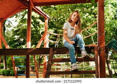 Girl 9 Years Old Cheerfully Sits Grimacing On A Wooden Playground Lifestyle Blond Long Hair Contagious Laughter Model Childhood Holidays Summer