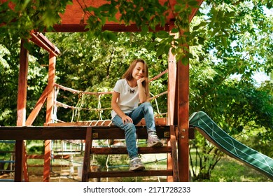 Girl 9 Years Old Cheerfully Sits Grimacing On A Wooden Playground Lifestyle Blond Long Hair Contagious Laughter Model Childhood Holidays Summer