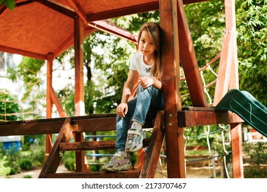 Girl 9 Years Old Cheerfully Sits Grimacing On A Wooden Playground Lifestyle Blond Long Hair Contagious Laughter Model Childhood Holidays Summer