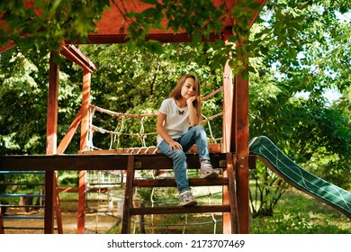 Girl 9 Years Old Cheerfully Sits Grimacing On A Wooden Playground Lifestyle Blond Long Hair Contagious Laughter Model Childhood Holidays Summer