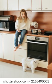 Girl 9 Years Old With Long Hair Model Plays With Pet White Dog Maltese School Girl At Home Lifestyle In Beige Kitchen No Allergy Veterinarian